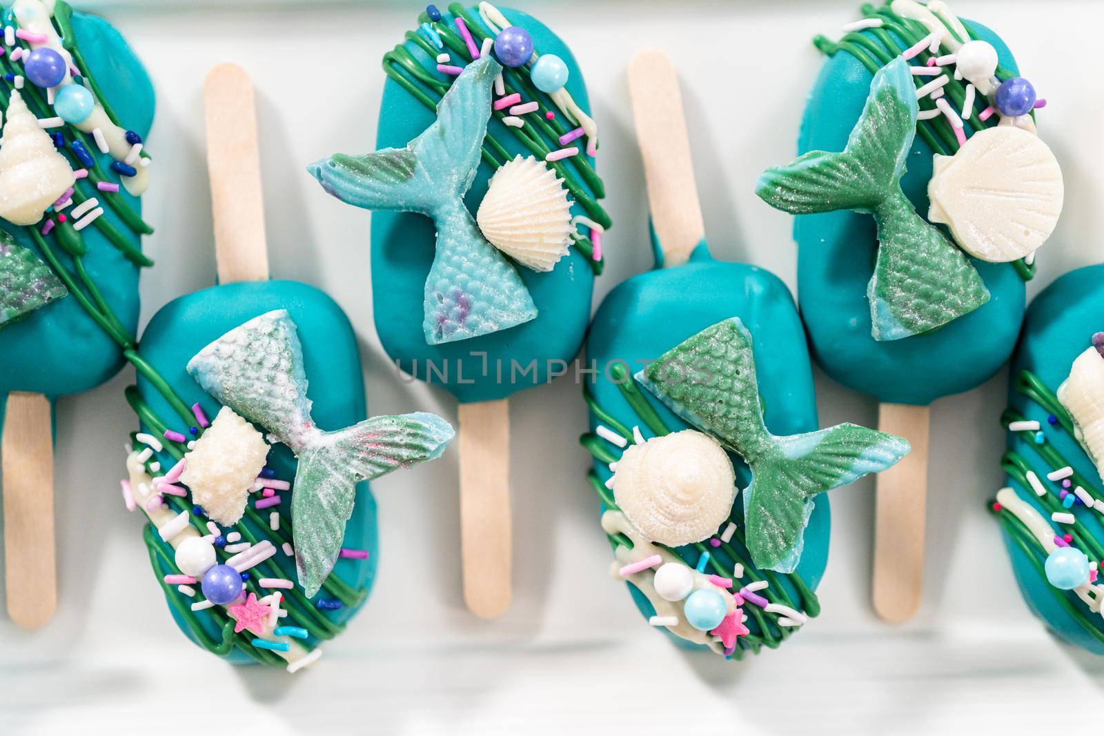 Mermaid cakesicles with drizzled chocolate, chocolate mermaid tails, seashells, and sprinkles.