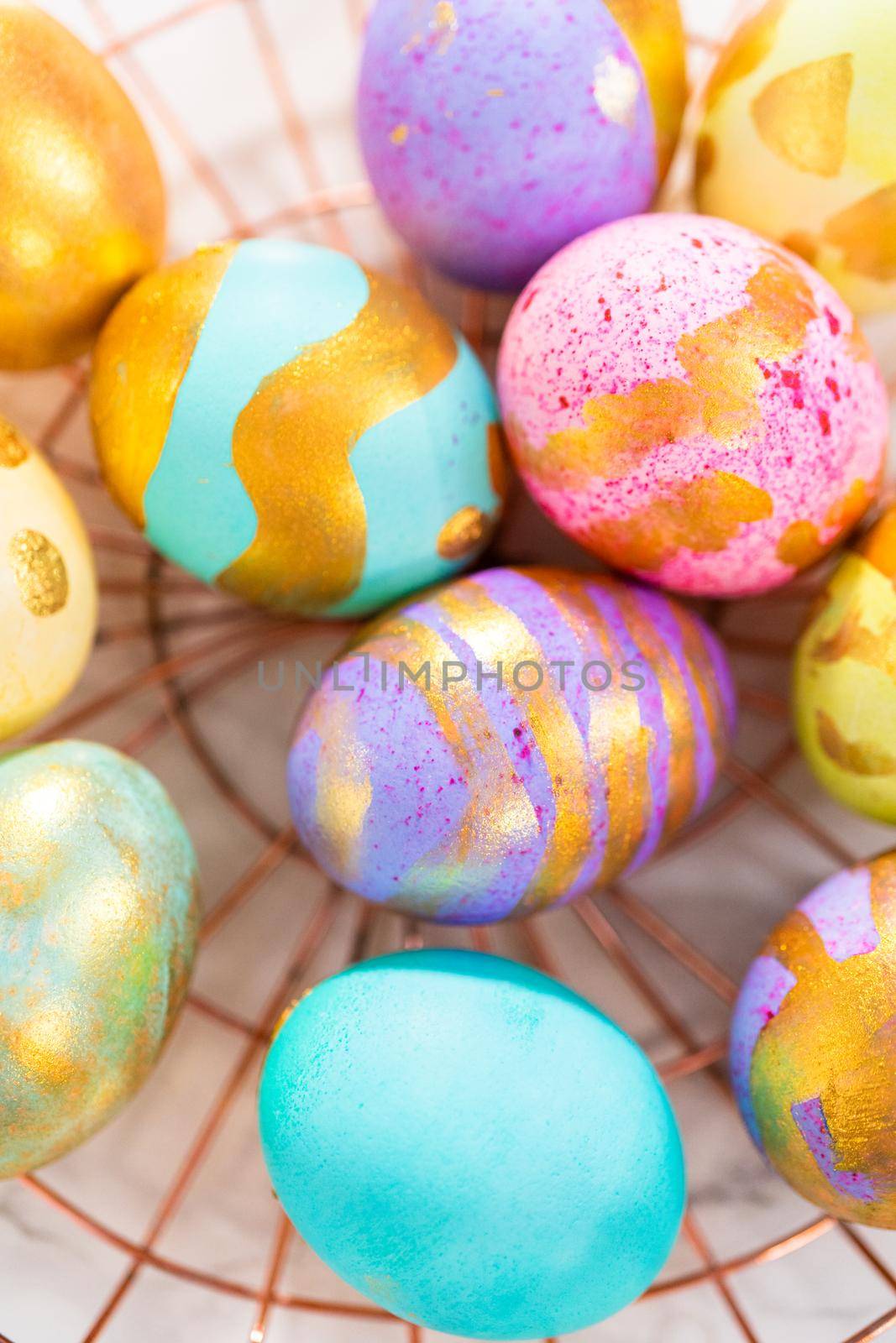 Colored and painted with gold hard-boiled eggs on a marble background.