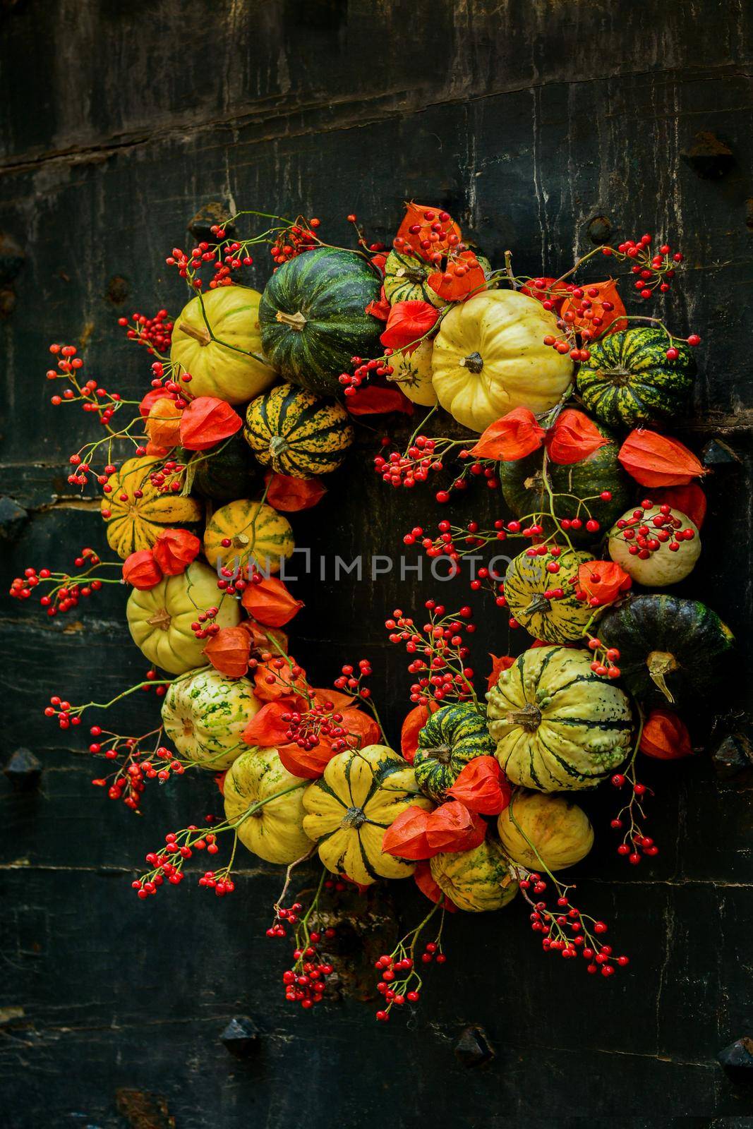 Handmade wreath of small pumpkins and zucchini on a black vintage door