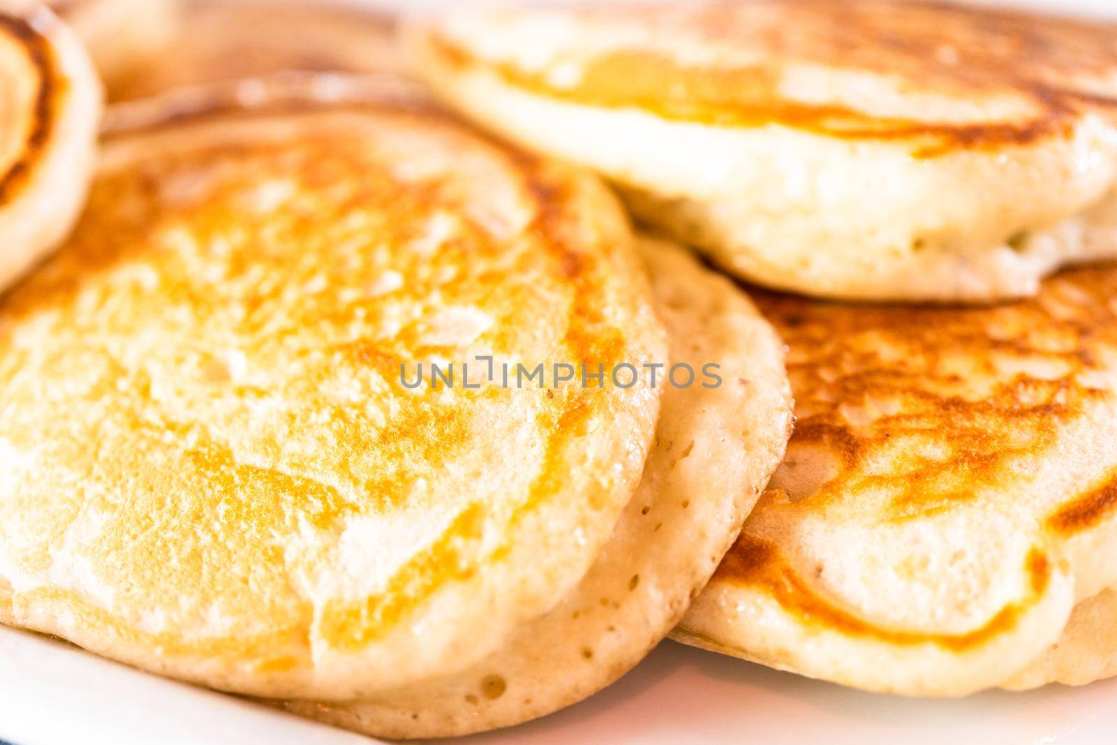 Freshly made pancakes on a white serving plate.