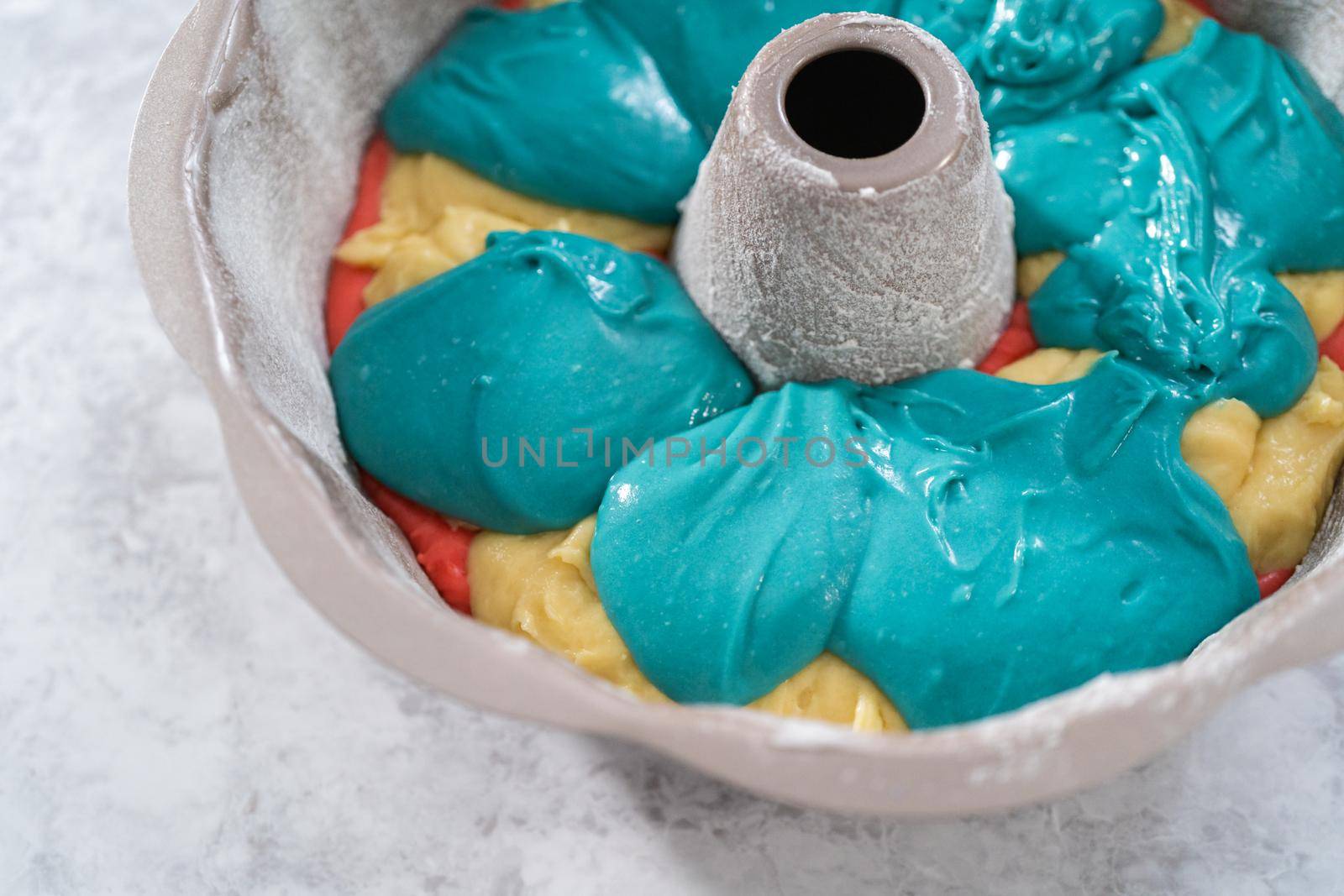 Filling bundt cake pan with red, white, and blue cake dought to bake July 4th bundt cake with chocolate stars.