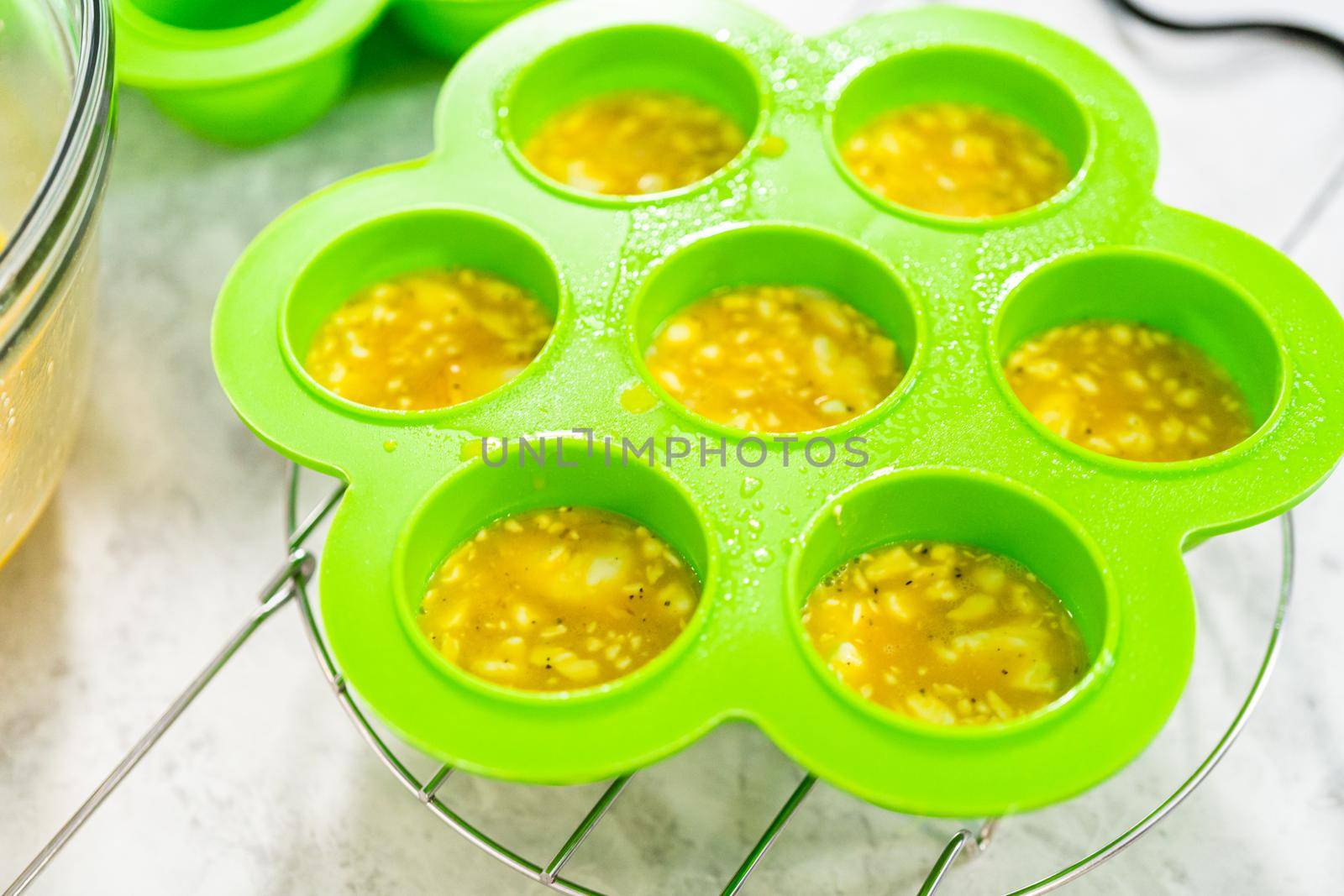 Filling silicone molds with egg mixture to make egg bites in a pressure cooker.