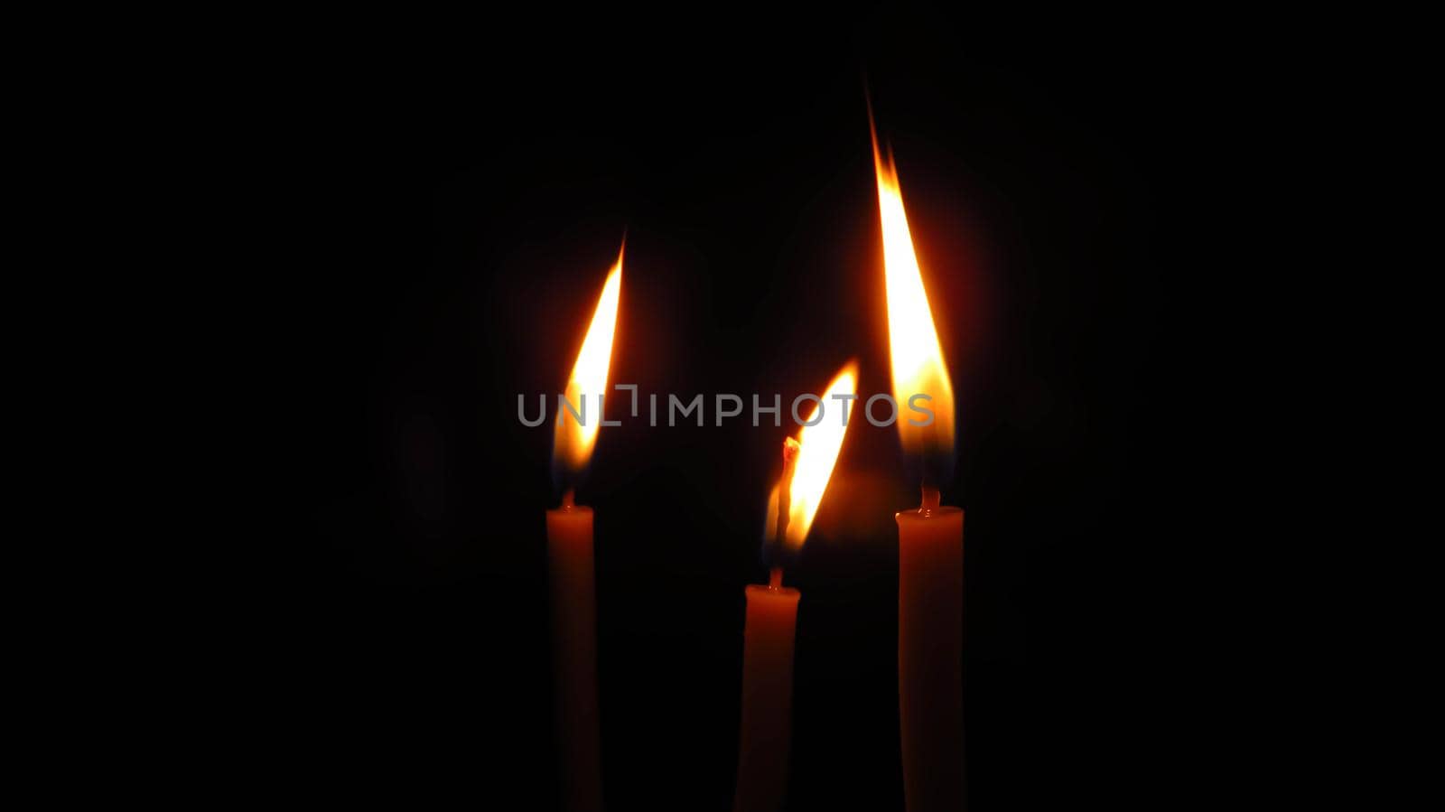 three mysterious church candles on a dark background.