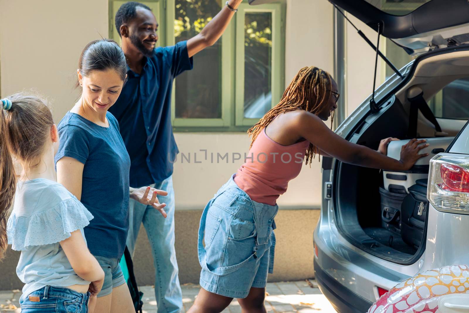 Diverse people loading luggage in trunk by DCStudio