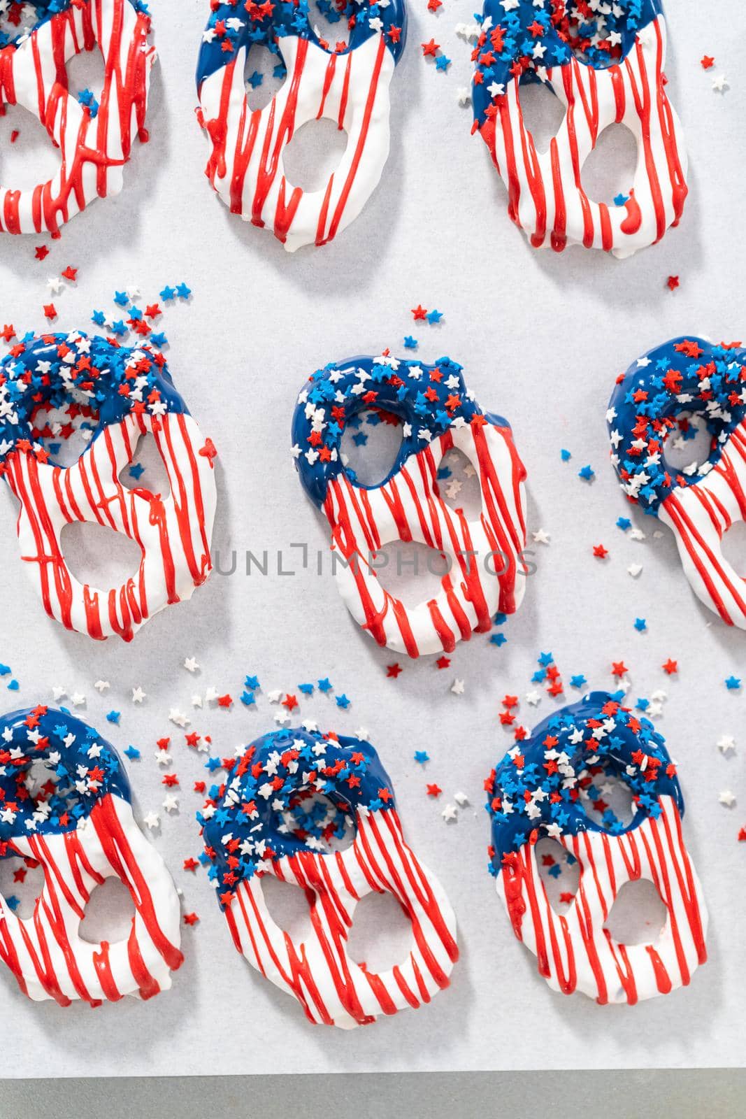 Dipping pretzels twists into melted chocolate to make red, white, and blue chocolate-covered pretzel twists.