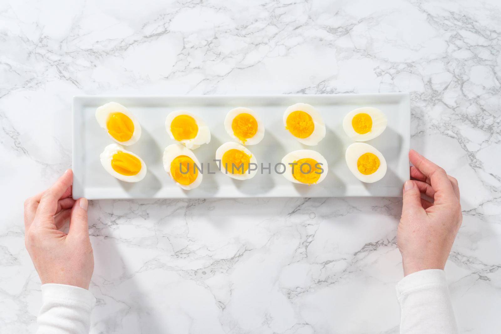 Sliced hard-boiled eggs on a white serving plate.