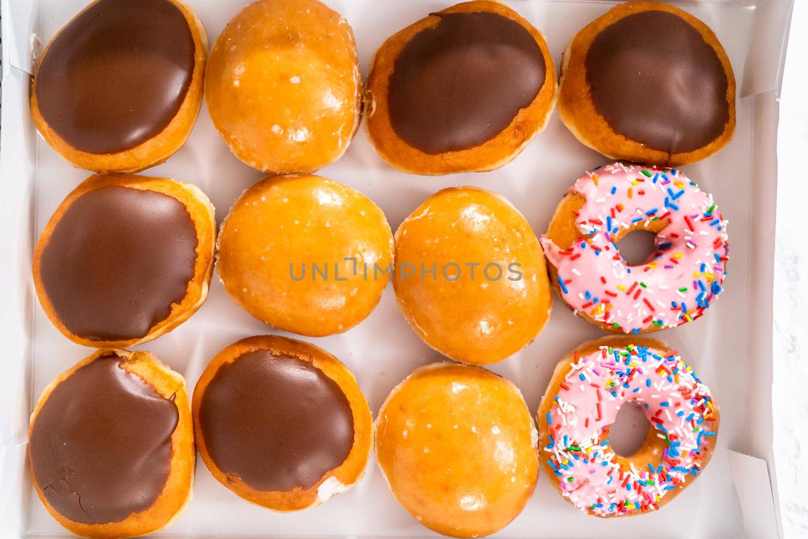 Variety of store-bought doughnuts in a white paper box.