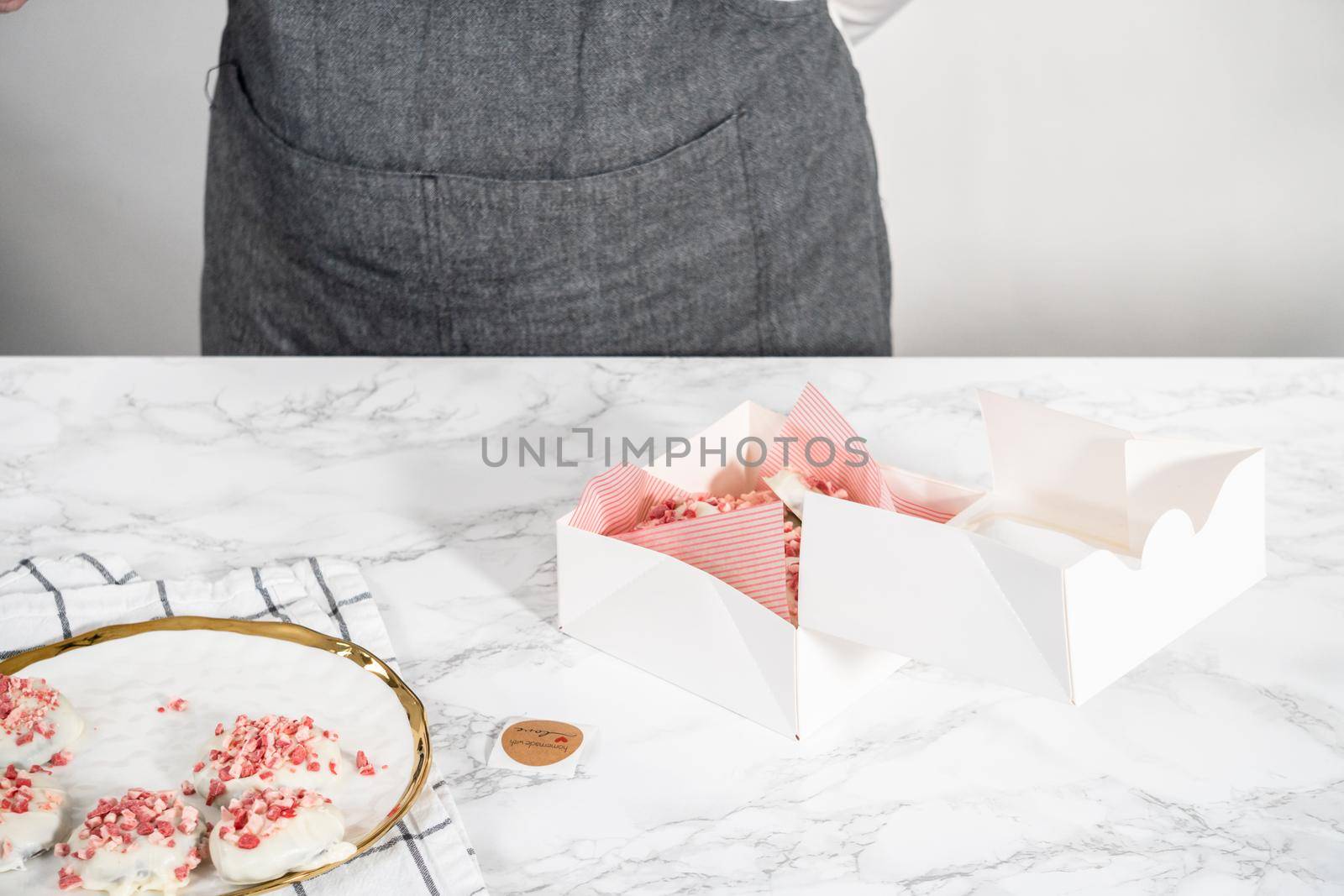 Packing freshly baked peppermint white chocolate cookies into a white paper box.