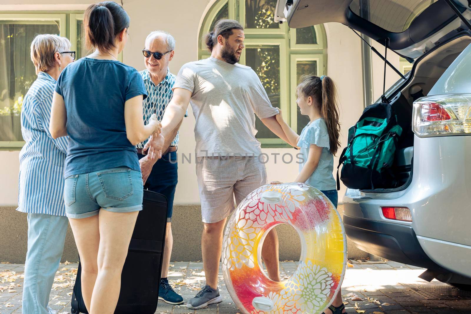 Caucasian people leaving on summer holiday, putting travel bags and inflatable in automobile trunk. European family travelling together on vacation journey, loading luggage and suitcase.