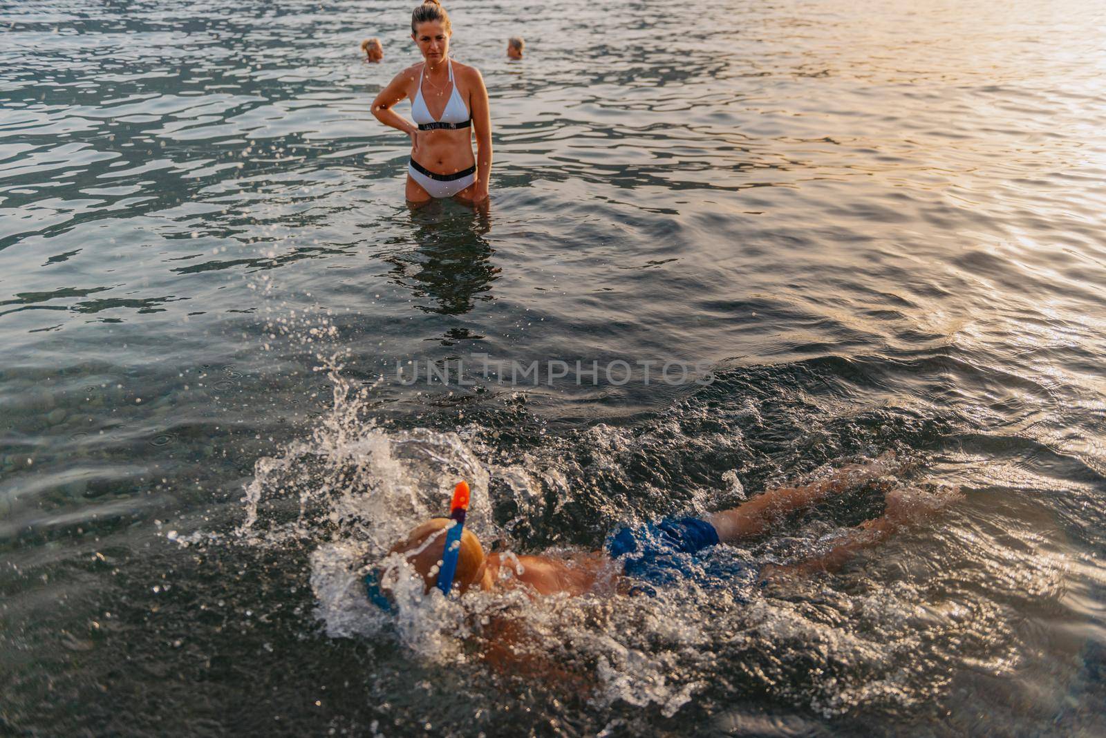 Cute happy little boy swimming and snorking in the sea. Child wearing snorkeling mask diving underwater, little boy enjoy swim underwater on tropical resort