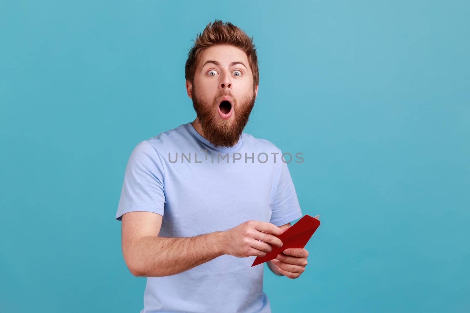 Man in T-shirt reading letter or greeting card, holding envelope, being astonished of shocked news. by Khosro1
