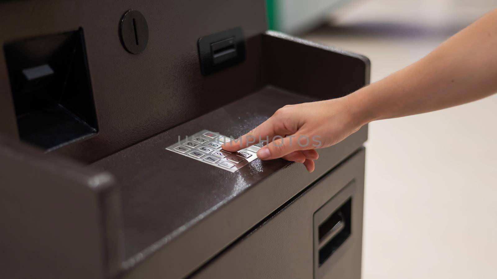 Faceless woman dialing bank card pin at ATM