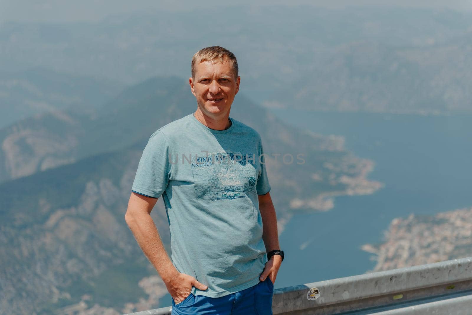 Man tourist enjoys the view of Kotor. Montenegro. Bay of Kotor, Gulf of Kotor, Boka Kotorska and walled old city. Travel to Montenegro concept. Fortifications of Kotor is on UNESCO World Heritage by Andrii_Ko