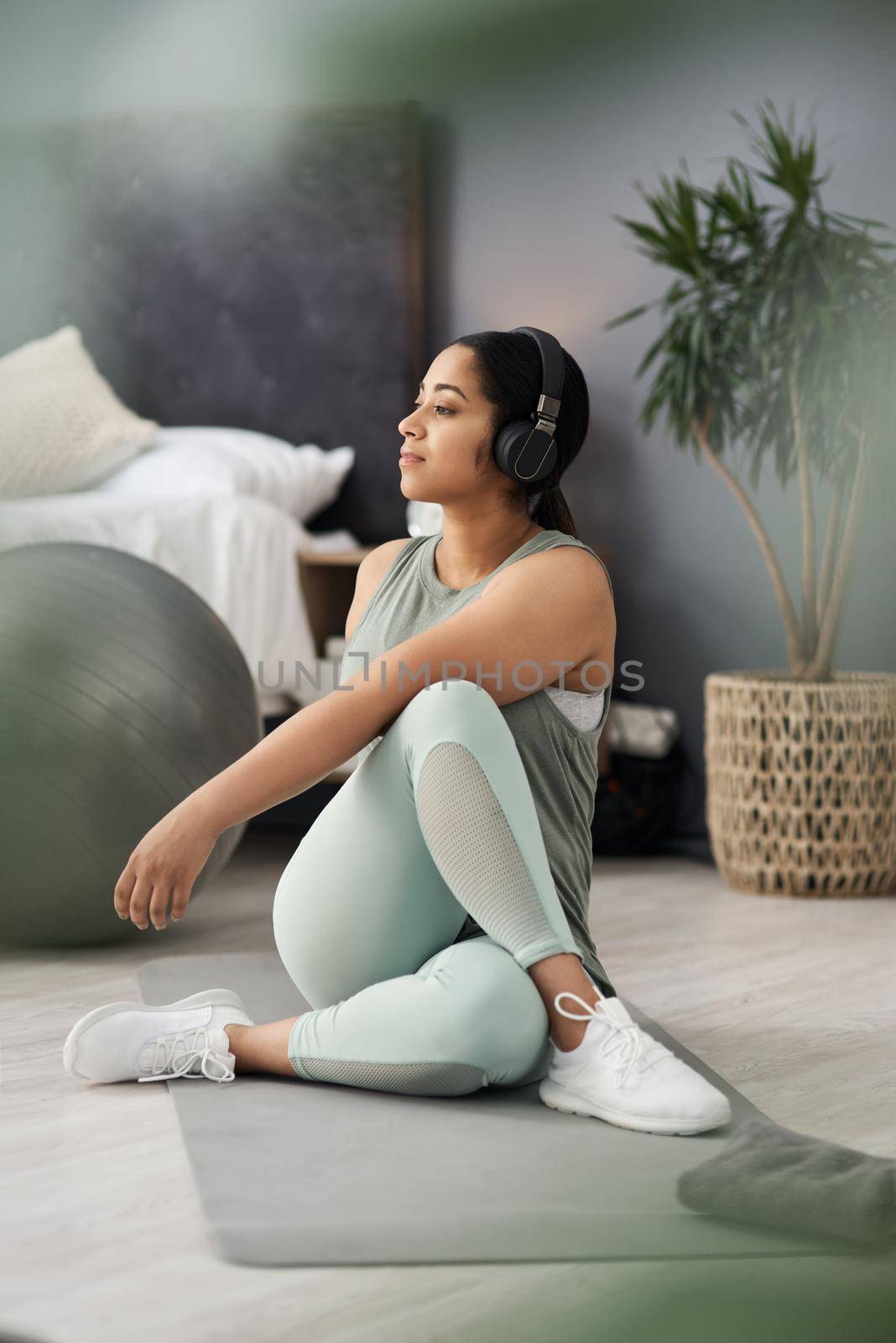 Getting a healthy start to her day. a sporty young woman listening to music while exercising at home