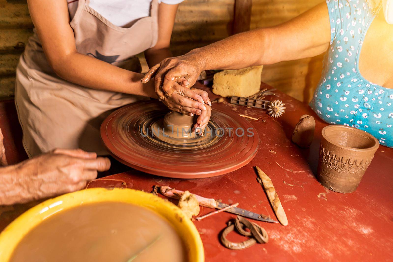 Unrecognizable artisan teaching how to mold handicrafts on an artisan lathe