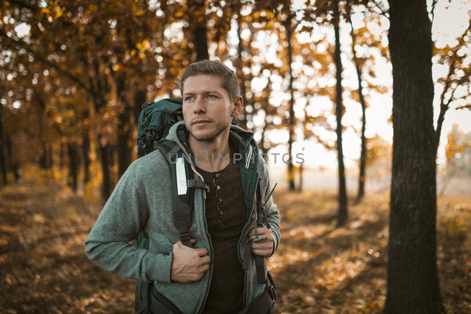 Smiling Tourist Walking Along A Forest Footpath Covered With Yellow Autumn Leaves, Happy Caucasian Guy With A Large Backpack Looks Around Walking In The Autumn Forest