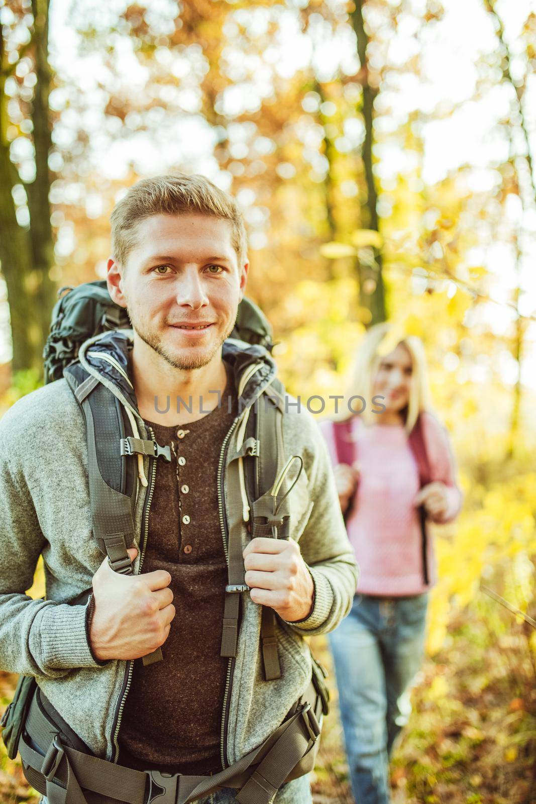 Two backpackers tourists in autumn nature, cheerful couple, caucasian man and woman set off for new adventures, journey in nature. Hiking concept.