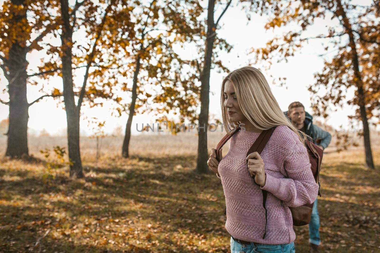 Happy Travelers with backpacks begins their journey in the autumn Sunny forest by LipikStockMedia