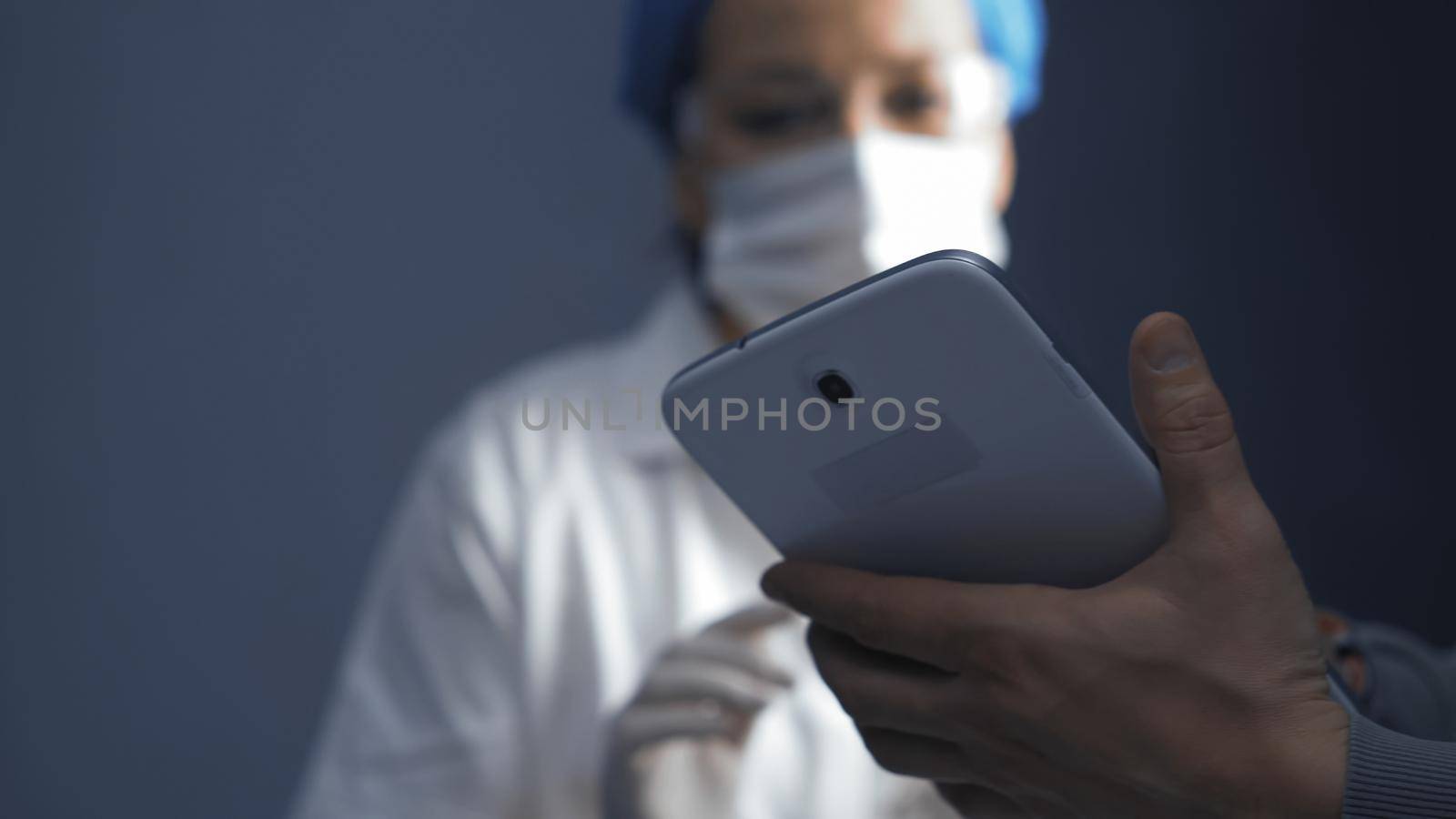 Female doctor or nurse learning to use an electronic notepad gadget. Focus on electronic device in male hands in the foreground. Education concept. Close up shot. Toned image by LipikStockMedia