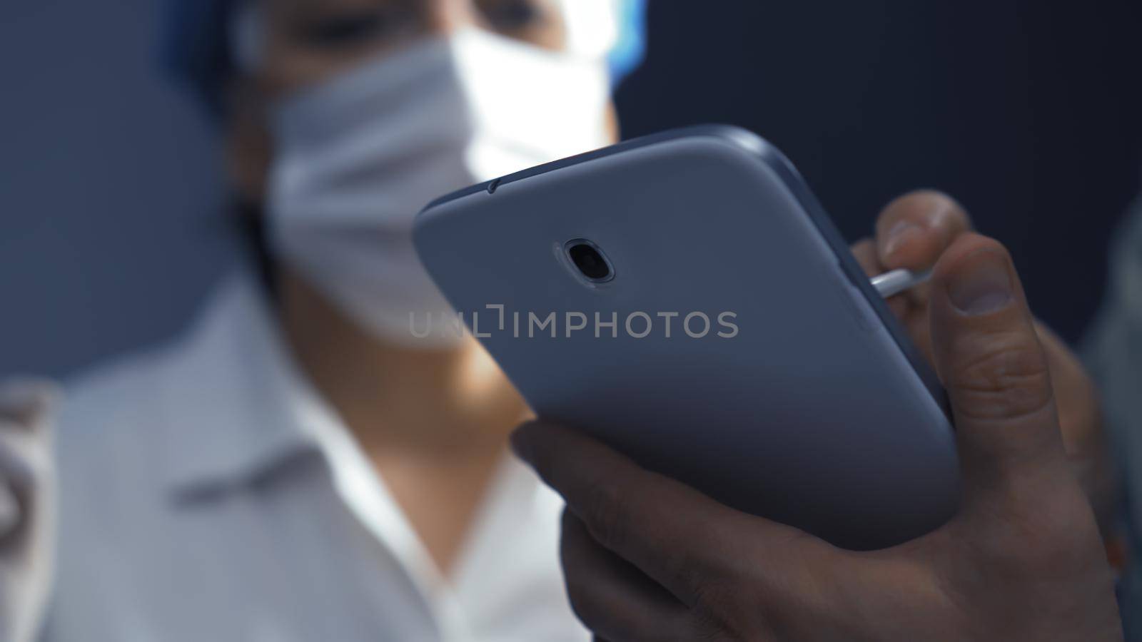 Doctor or nurse learning to use electronic tablet gadget. Selective focus on digital device in male hands in foreground. Learning concept. Close up shot.