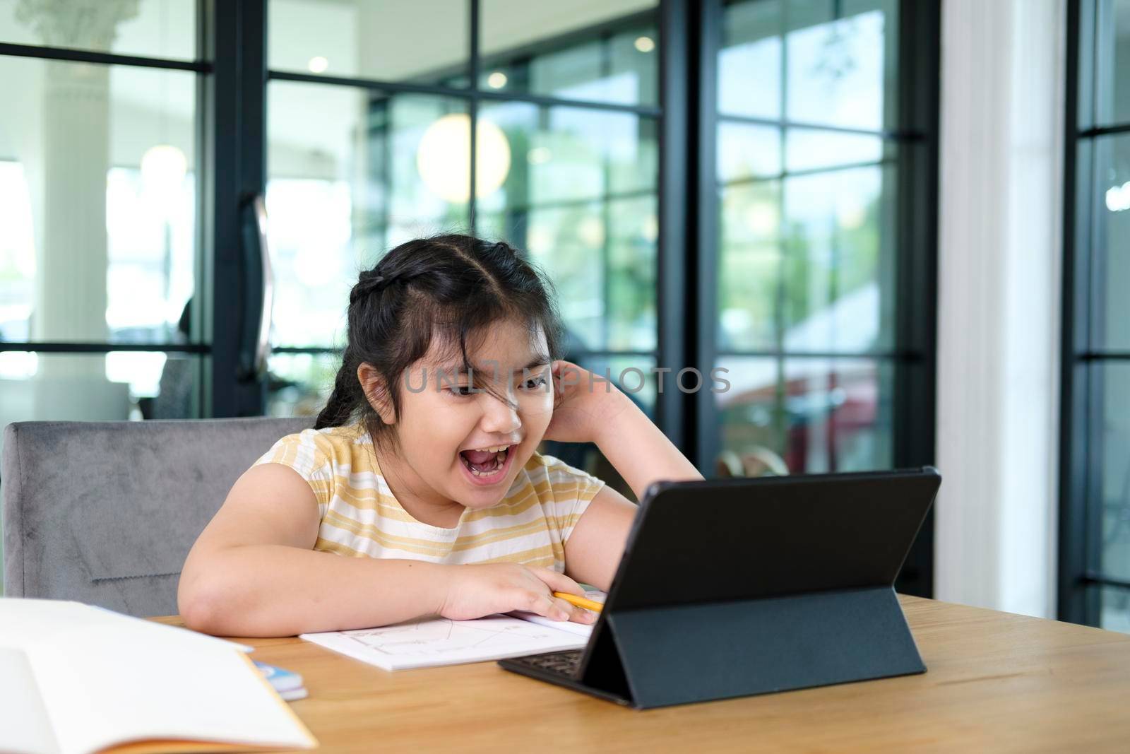 Cute and happy little girl children using laptop computer, studying through online e-learning system.