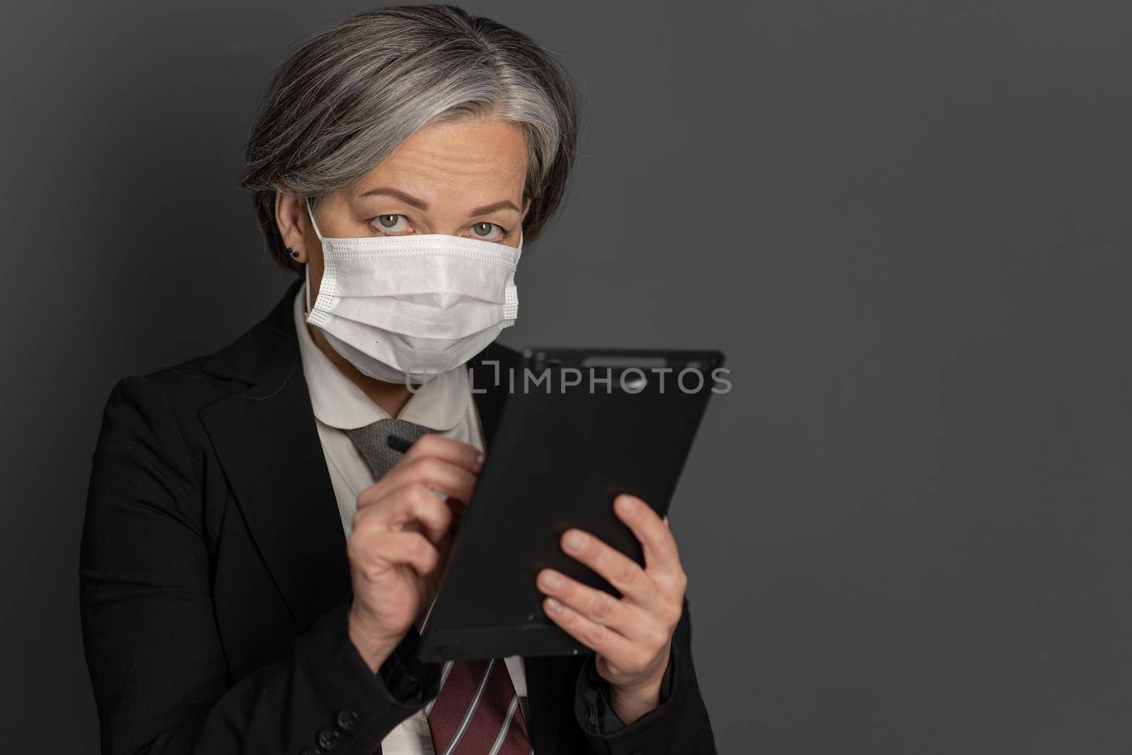 Caucasian businesswoman in protective mask works looking at camera. Selective focus on female eyes. Empty space for text at right side by LipikStockMedia