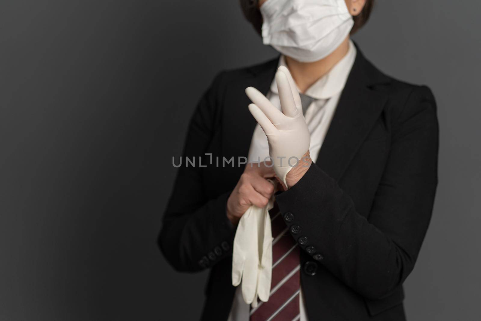 Business Woman in protective mask put on disposable gloves. Close up shot. Focus on female hand in foreground. Pandemic concept.