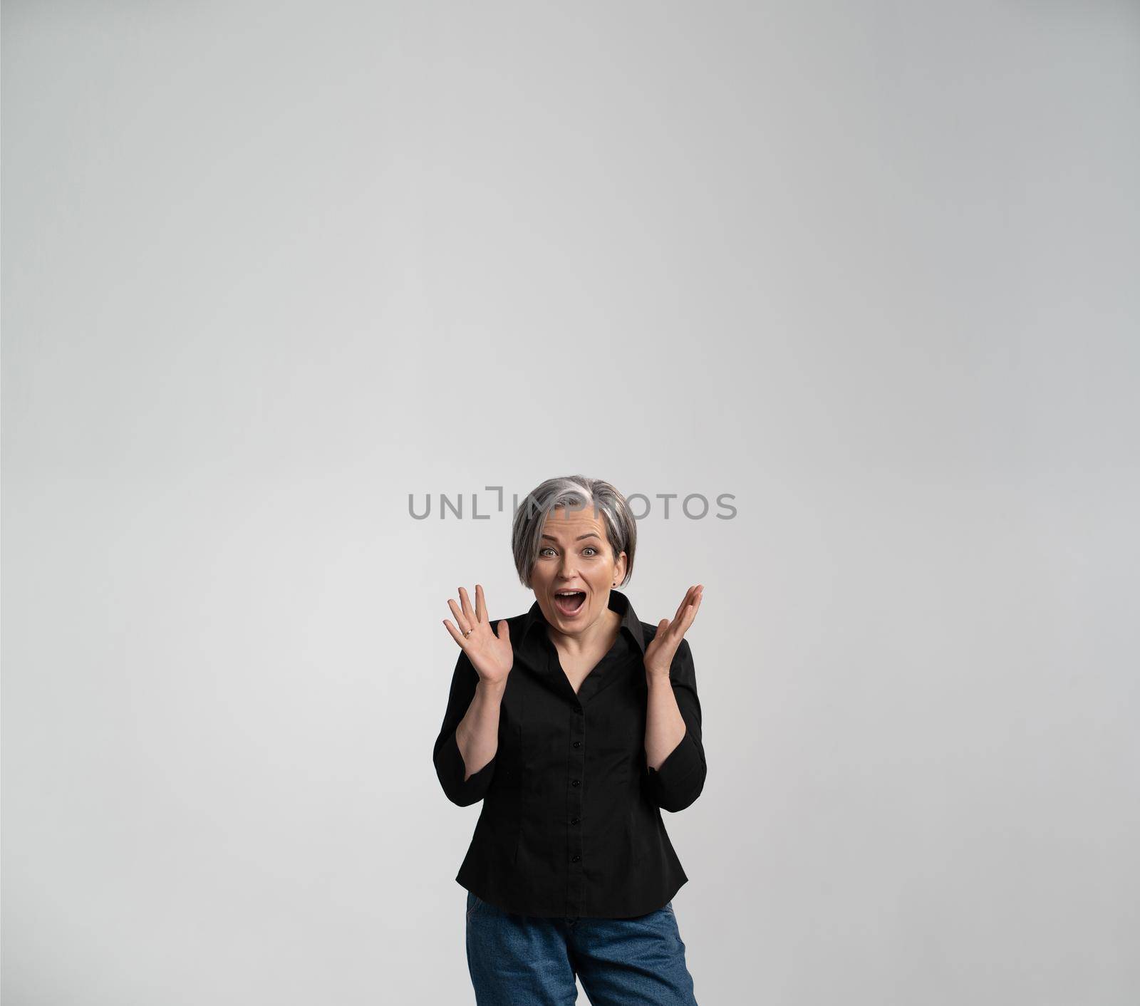 Surprised mature woman with opened mouth and palms. Positively shocked Caucasian lady in black shirt. Advertisement concept. Amazement concept. Square template with textspase.