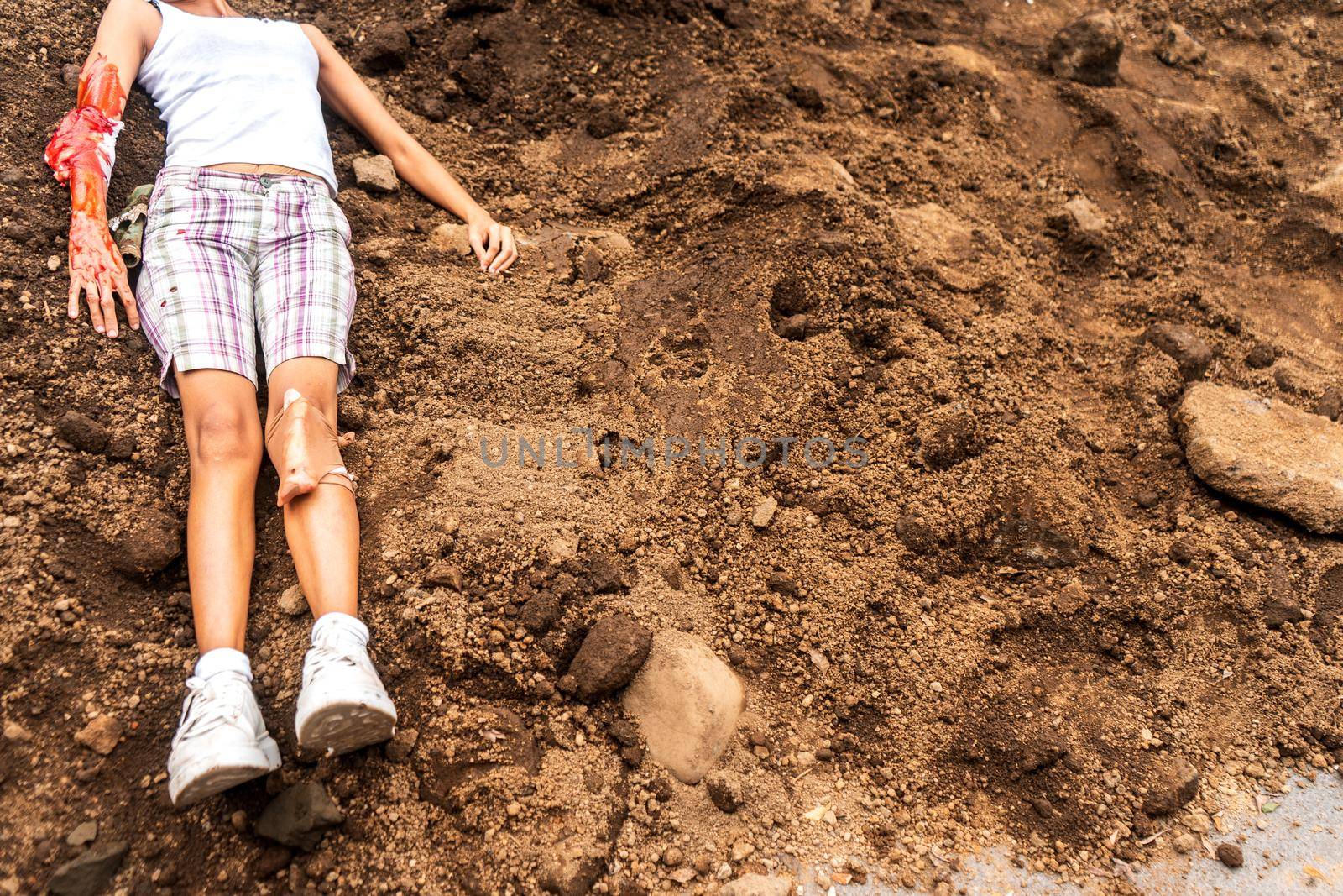 Horizontal photo of an unrecognizable young Latin woman victim of femicide lying on a pile of dirt