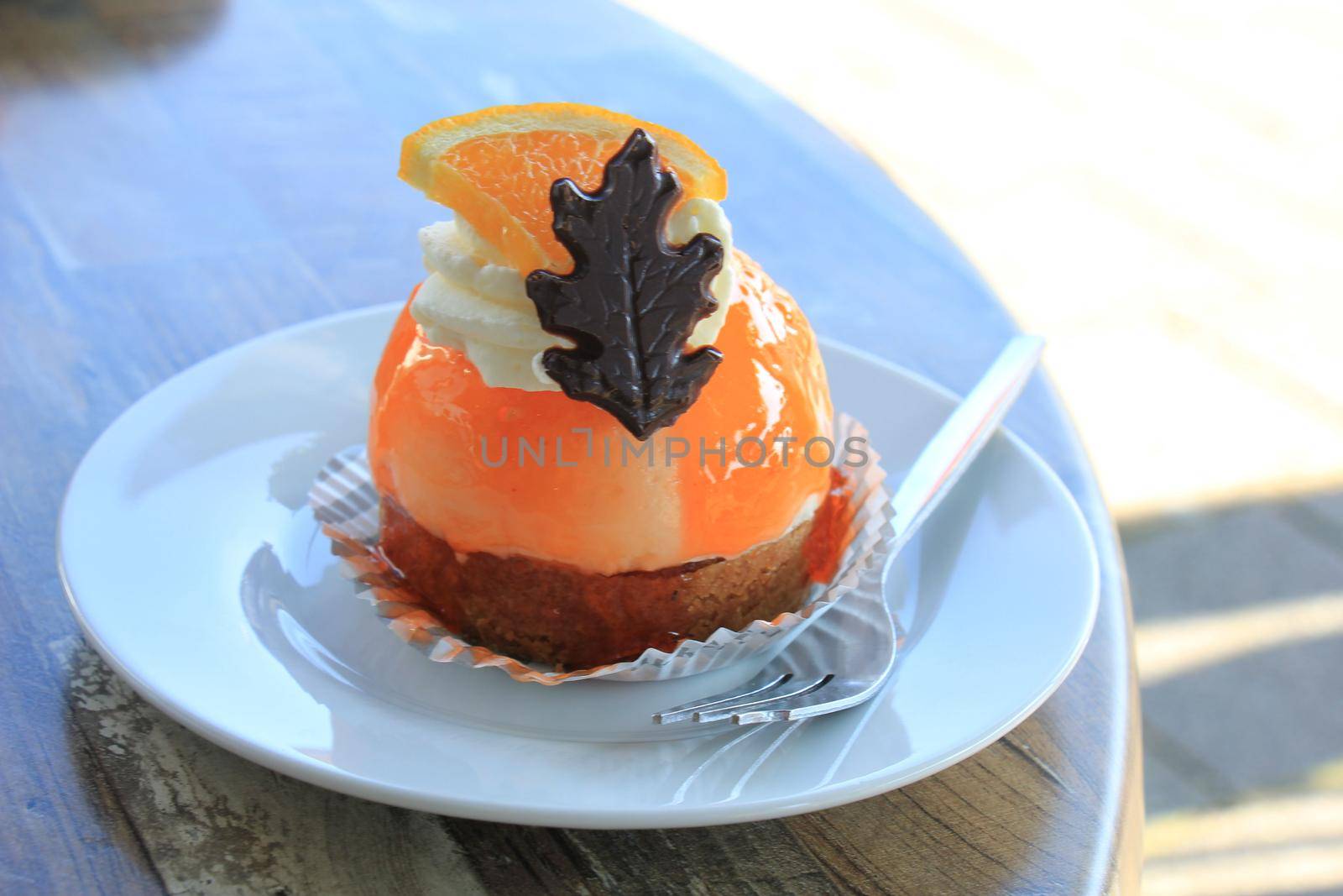 Fresh orange mousse confectionery, with cream and a chocolate decoration by studioportosabbia
