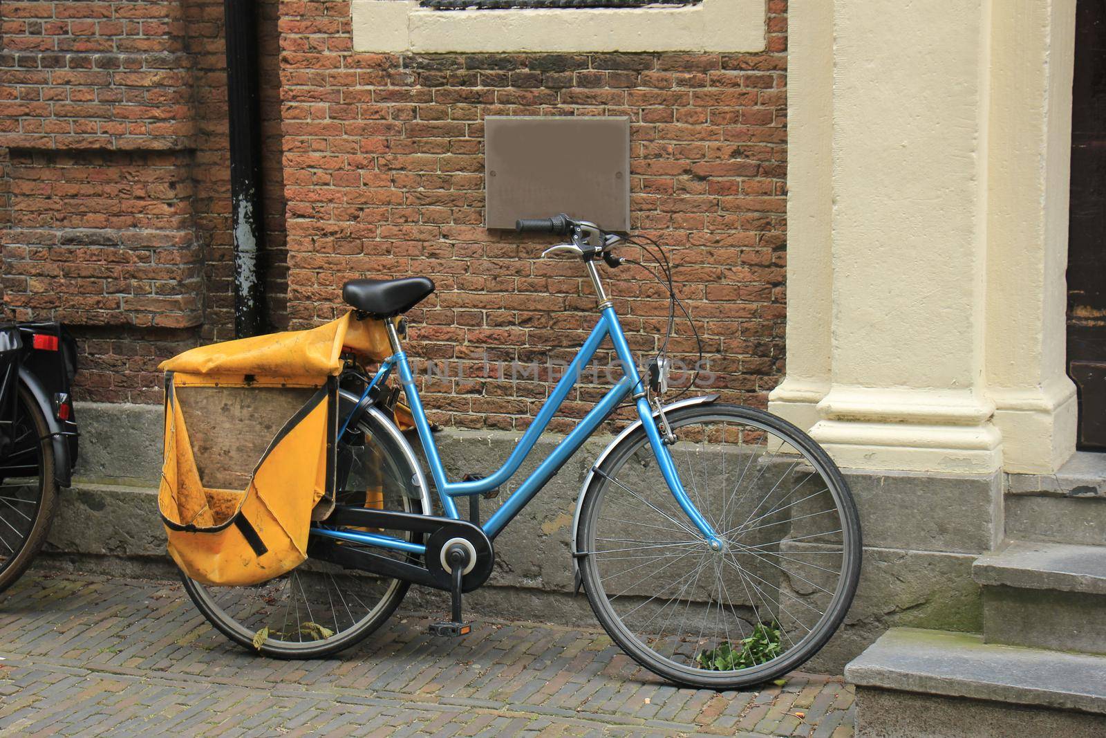 An old light blue bike parked near a brick wall