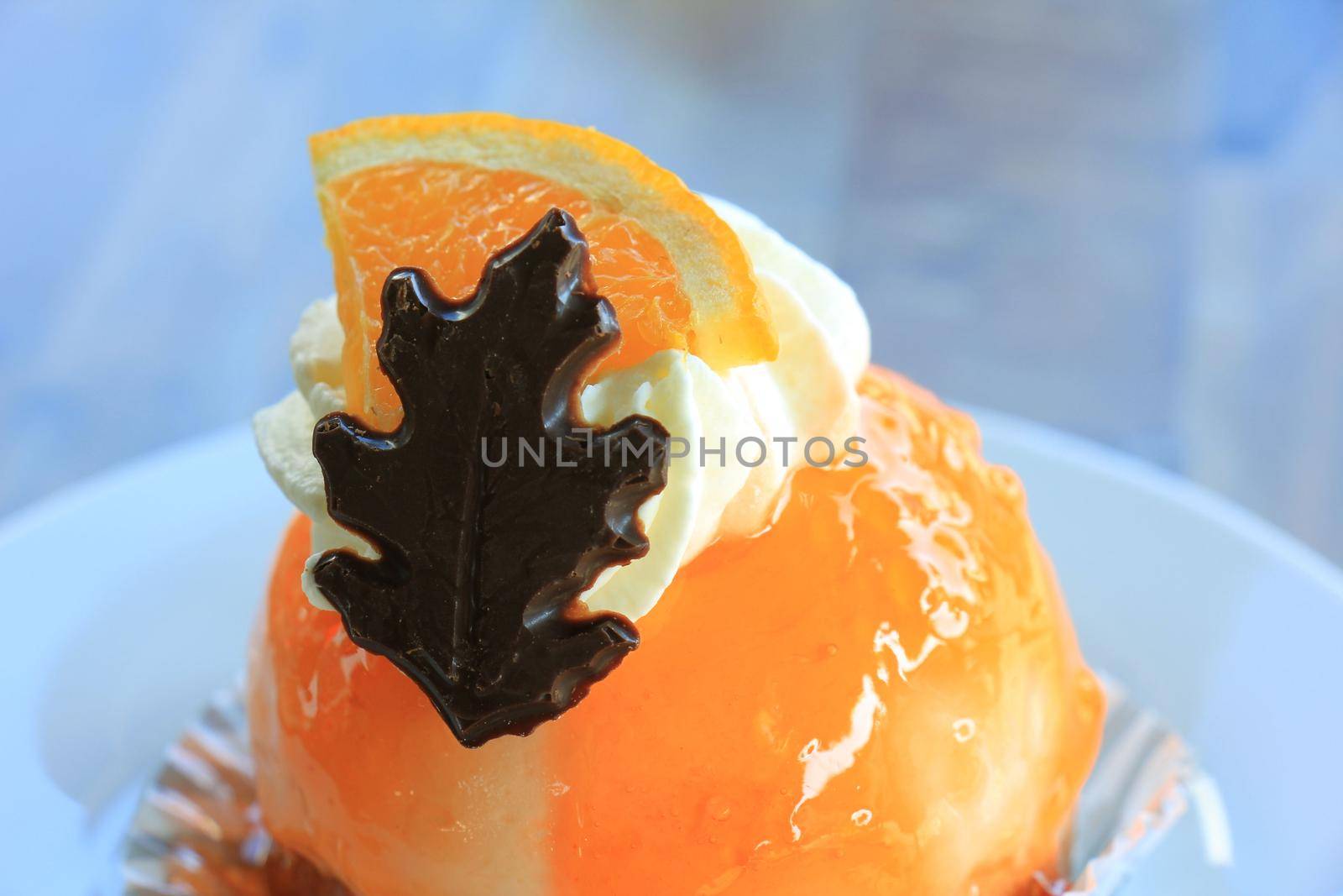 Fresh orange mousse confectionery, with cream and a chocolate decoration