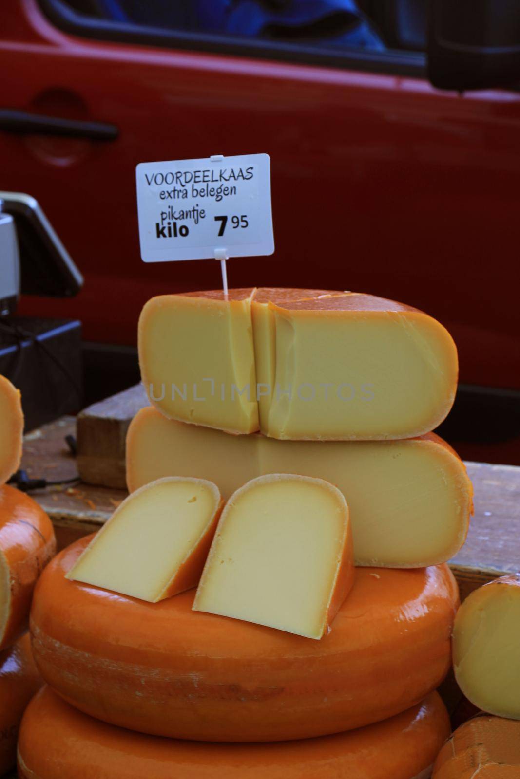 Traditional Dutch cheeses on display on a market stall. Text on tag in Dutch: Special offer cheese, extra old and spicy, one kilo for € 7.95.