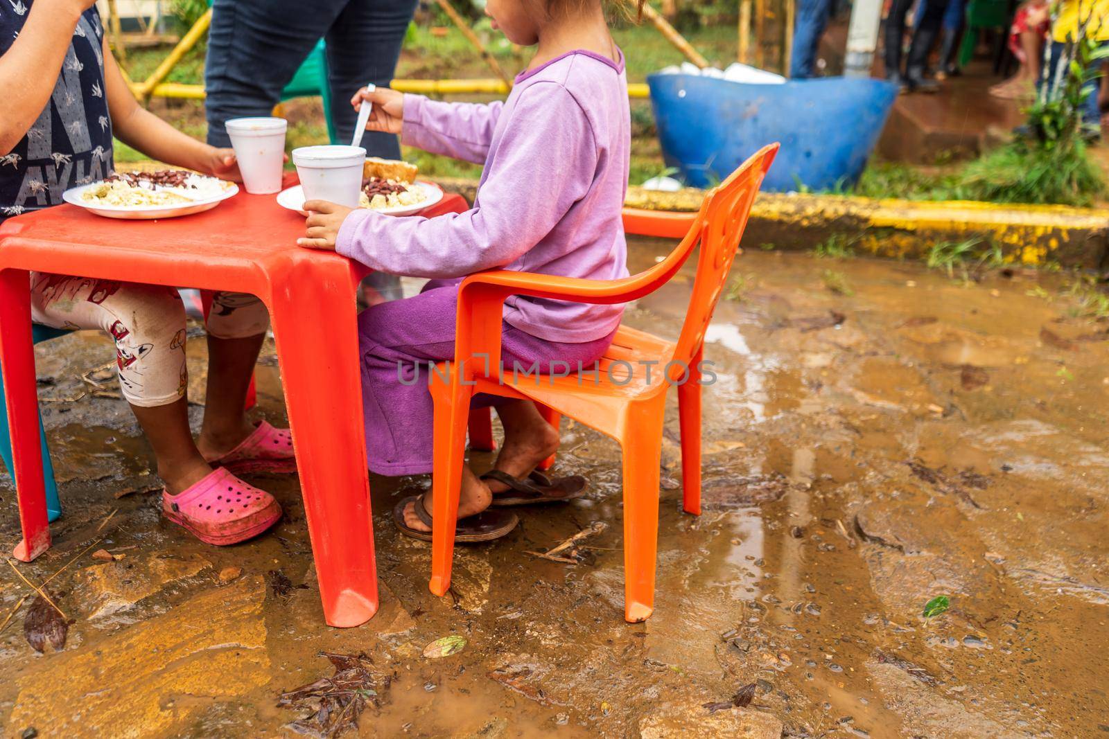 Unrecognizable orphaned Latino children sitting eating in Latin America
