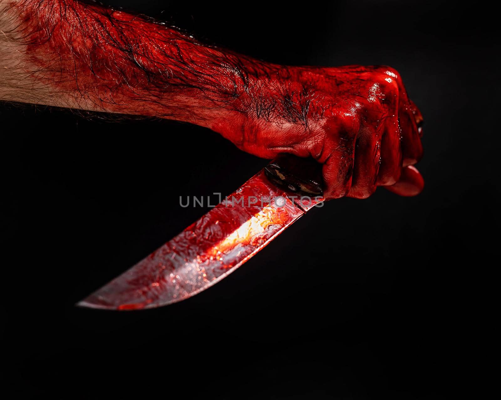 Man holding knife with bloody hand on black background. by mrwed54