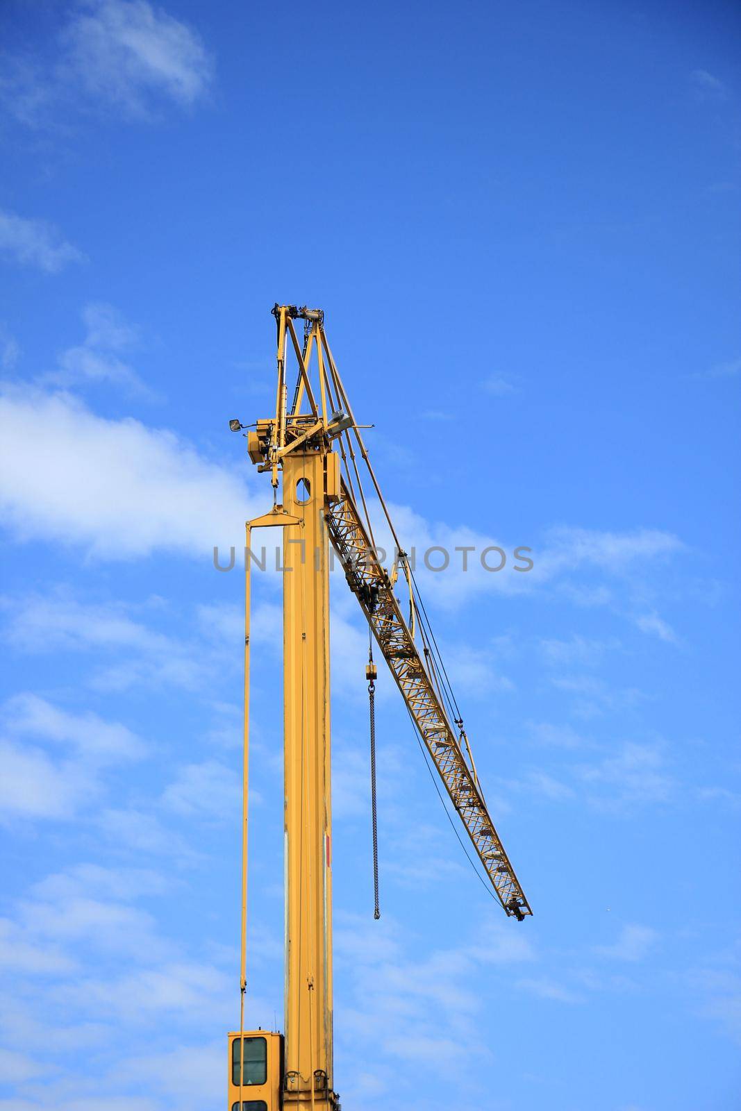 Tall construction crane at a construction site by studioportosabbia