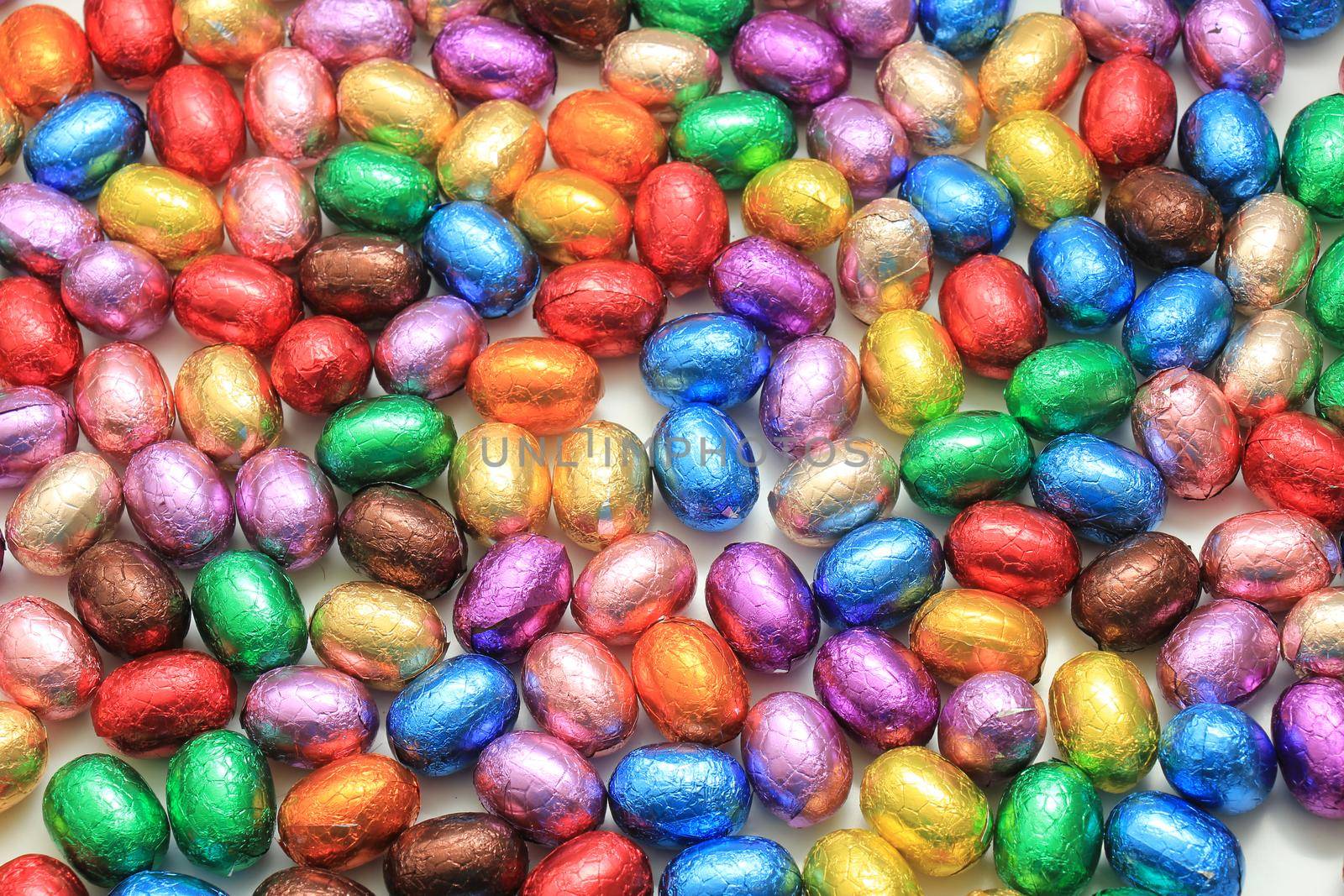 Big pile of colorful wrapped chocolate easter eggs by studioportosabbia