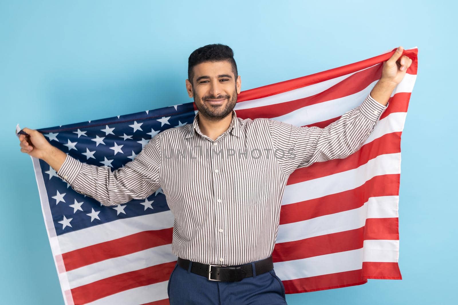 Smiling businessman holding USA flag and looking at camera with smile, celebrating national holiday. by Khosro1