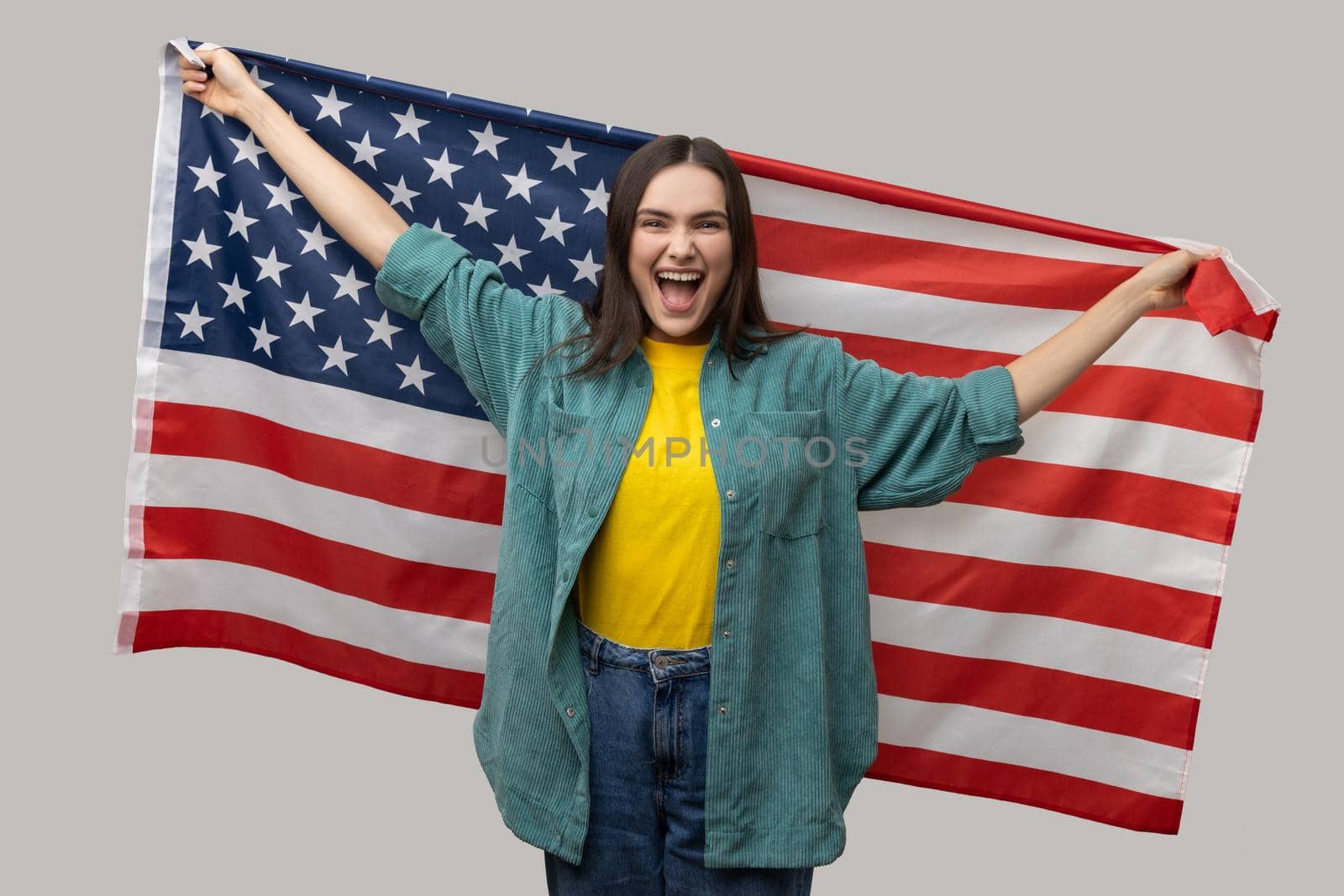 Positive woman standing with raised arms, holding USA flag, celebrating national holiday, rejoicing. by Khosro1