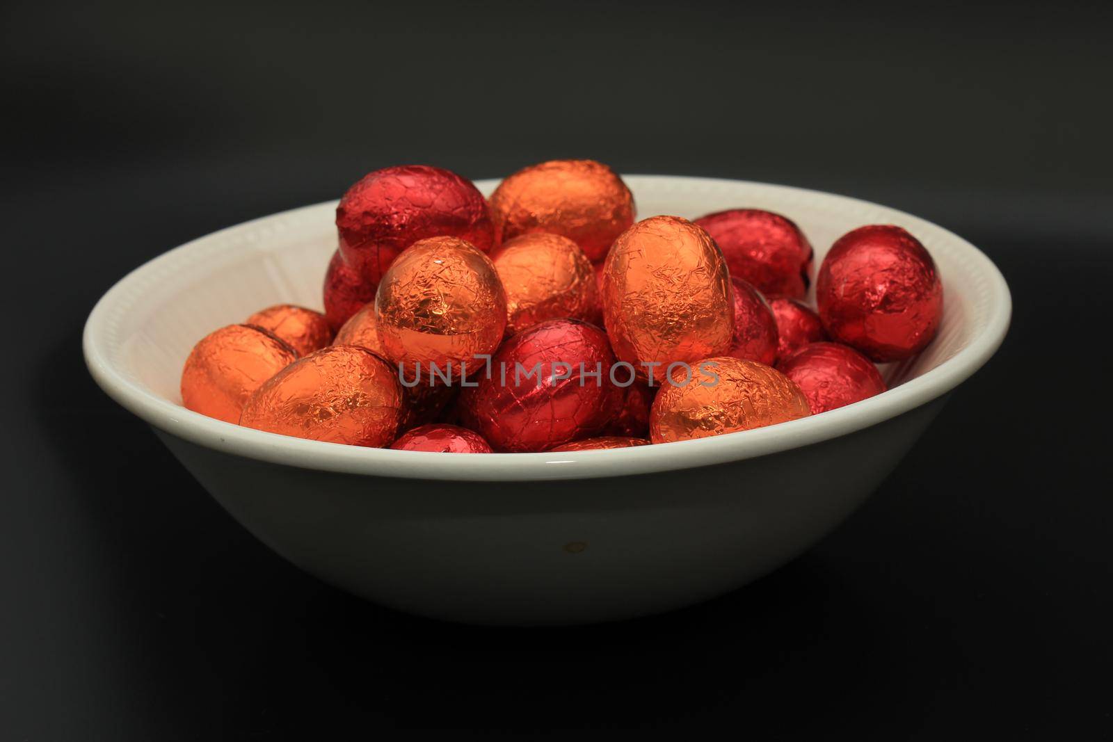 Foil wrapped chocolate easter eggs in a white porcelain bowl