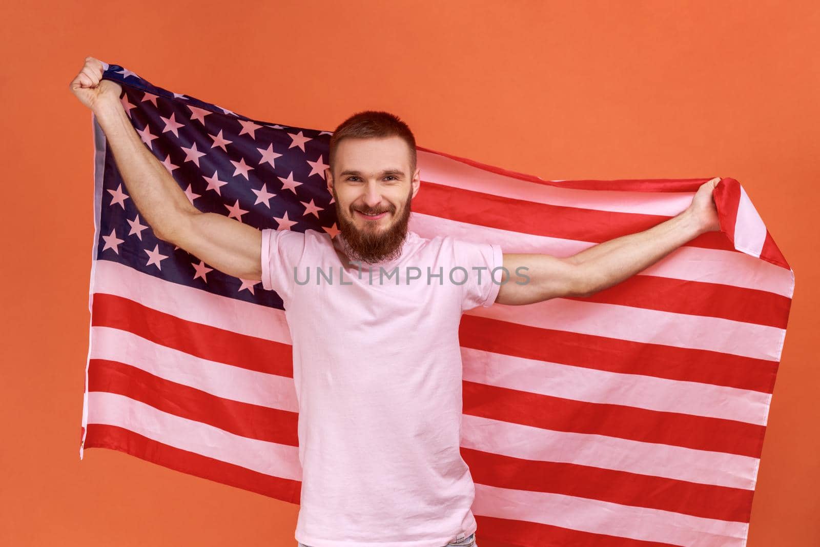 Man holding USA flag, looking at camera with toothy smile, proud of his social security in country. by Khosro1