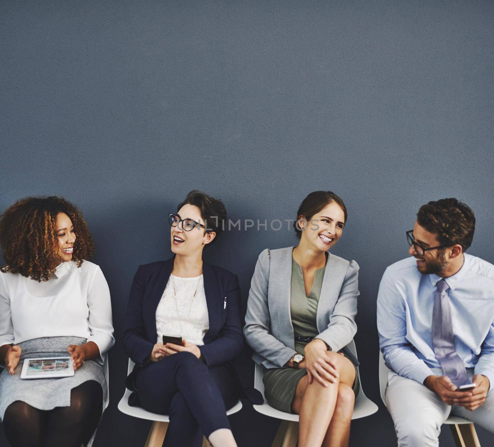 Waiting for an interview, connected, communication and network of diverse businesspeople using multimedia technology. Happy professional group sitting in a row, applying for an International job.