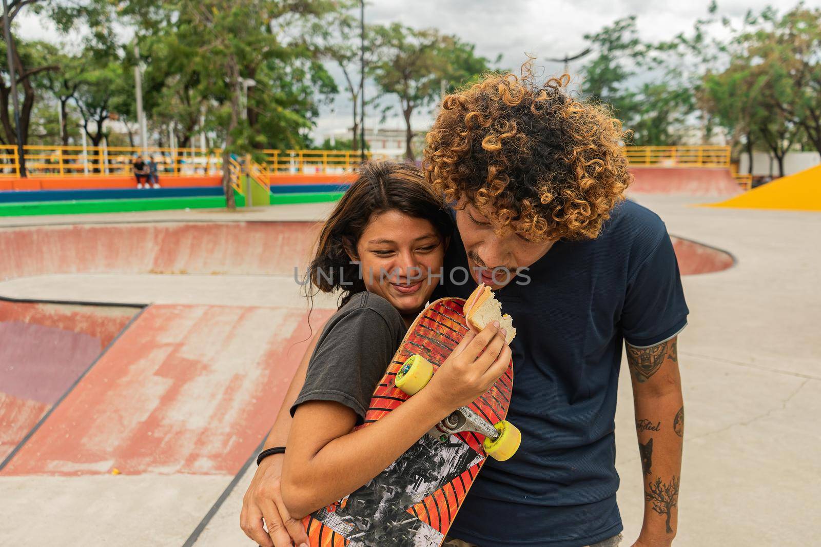 Latin couple in love skaters having a good time and eating in a park outdoors in Managua, Nicaragua
