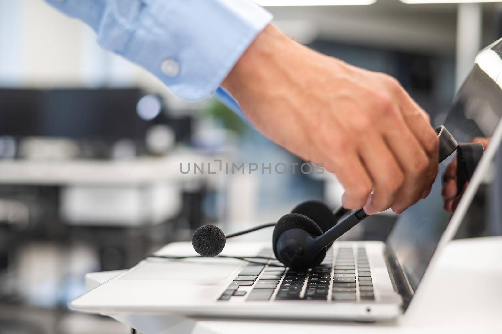 A man puts a headset on a laptop keyboard in the office