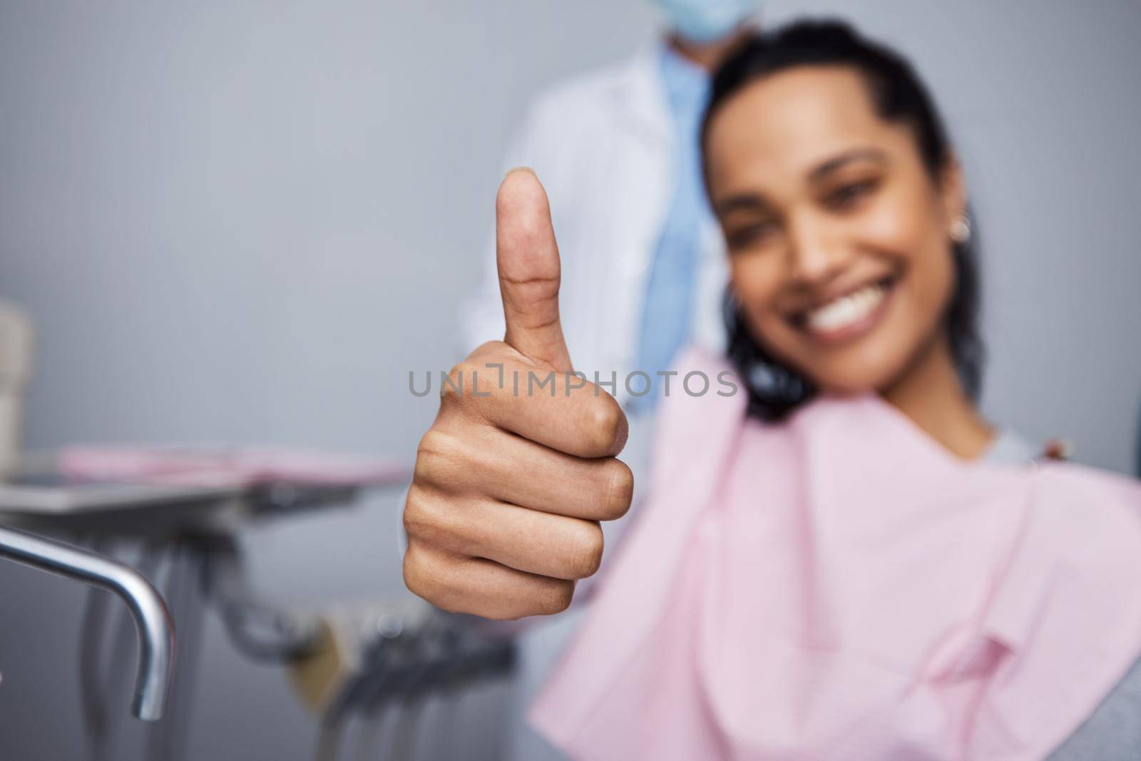 Pain free is the way for me. Portrait of a young woman showing thumbs during her dental appointment. by YuriArcurs