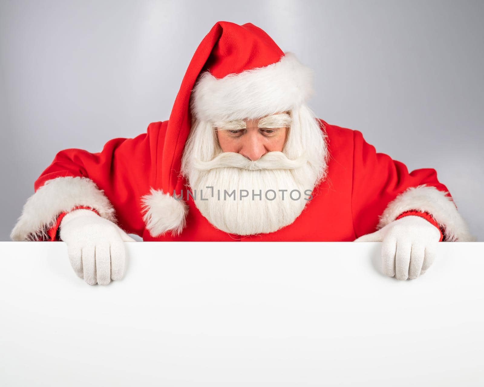 Santa Claus peeks out from behind an ad on a white background. Merry Christmas. by mrwed54