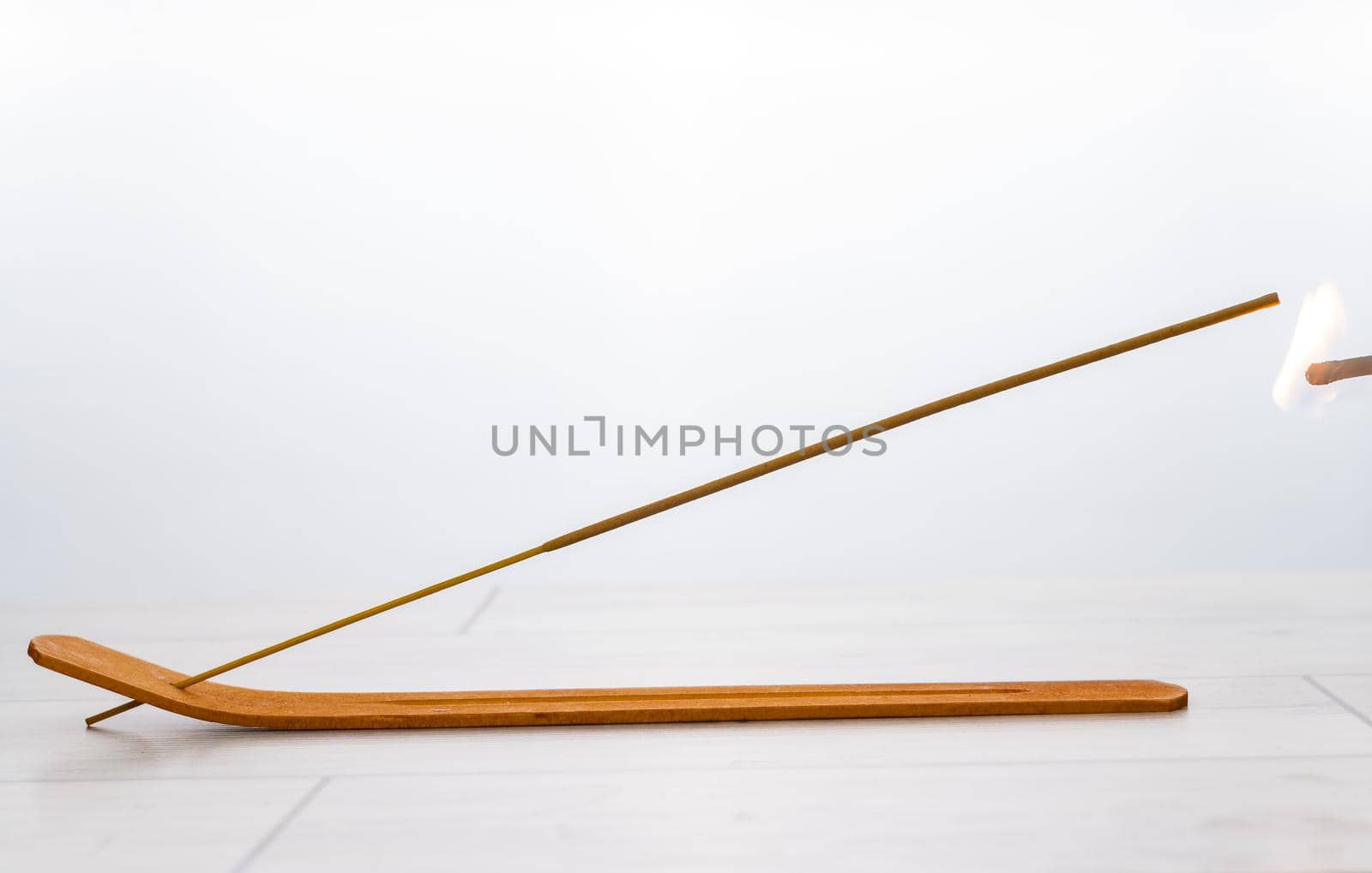 lighted incense stick on its stand on a white background and copy-space