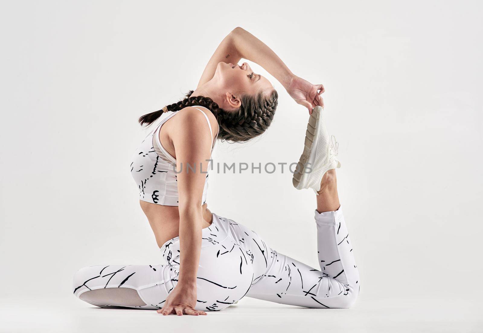 Chin up princess, or the crown slips. Studio shot of a sporty young woman exercising against a white background. by YuriArcurs