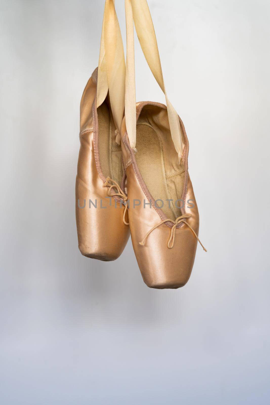 ballet slippers with orange ribbon on a wooden floor and white background