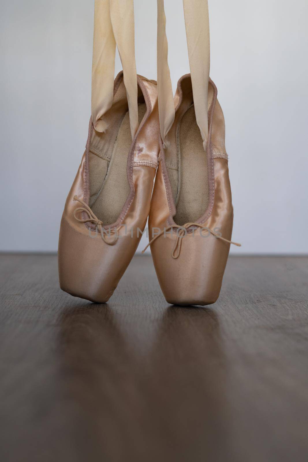 ballet slippers with orange ribbon on a wooden floor and white background